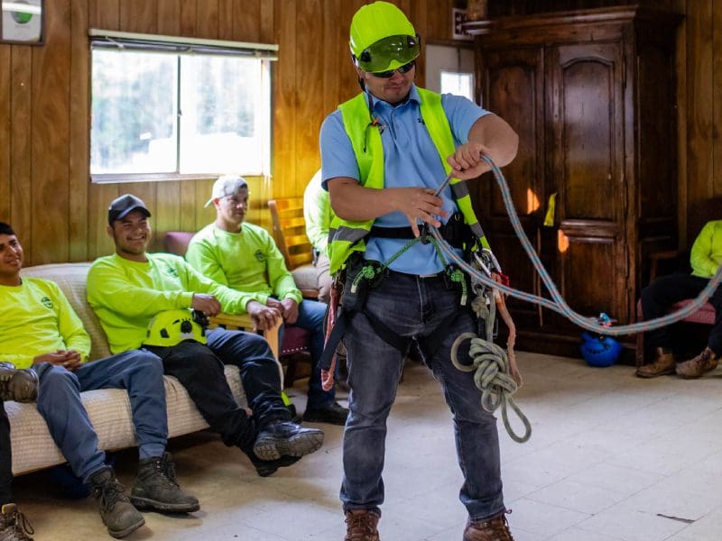 Worker demonstrating rope safety techniques indoors to colleagues.